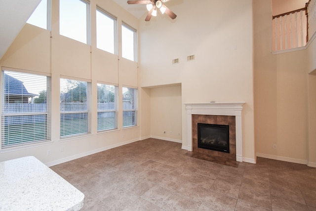 28015 Silverstream Ct, Fulshear, TX 77441 - unfurnished living room with a high ceiling, ceiling fan, a tile fireplace, and light tile patterned floors