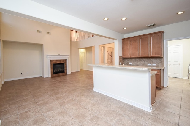 28015 Silverstream Ct, Fulshear, TX 77441 - kitchen featuring backsplash, light tile patterned floors, recessed lighting, a tile fireplace, and brown cabinetry
