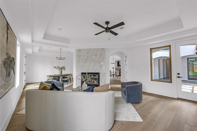 2031 Peppermill Rd, Houston, TX 77080 - living room featuring a tray ceiling, arched walkways, a ceiling fan, wood finished floors, and a premium fireplace