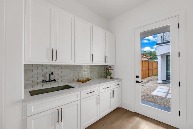 2031 Peppermill Rd, Houston, TX 77080 - kitchen with tasteful backsplash, light wood-style floors, white cabinetry, and light stone counters