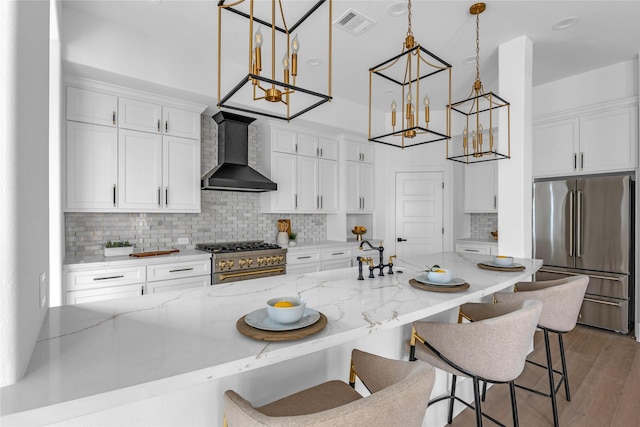 2031 Peppermill Rd, Houston, TX 77080 - kitchen with premium appliances, wall chimney range hood, white cabinetry, decorative backsplash, and a kitchen bar
