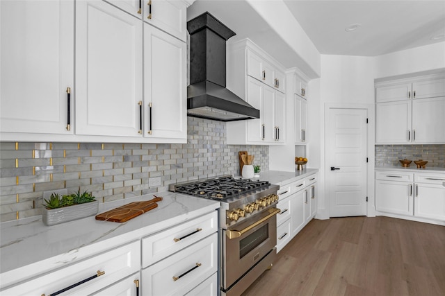 2031 Peppermill Rd, Houston, TX 77080 - kitchen featuring high end stove, wall chimney range hood, light wood-style flooring, backsplash, and white cabinetry