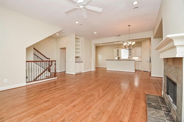 222 Knox St Unit F, Houston, TX 77007 - unfurnished living room featuring a tiled fireplace, a chandelier, ceiling fan, stairs, and recessed lighting