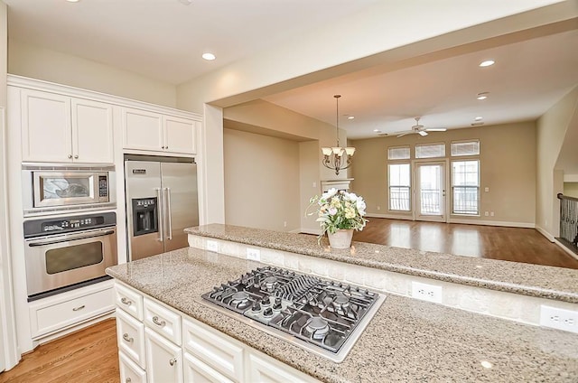 222 Knox St Unit F, Houston, TX 77007 - kitchen with built in appliances, white cabinetry, light stone counters, a chandelier, and light wood-style flooring