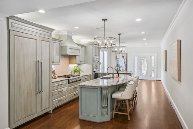 1114 W Cottage St, Houston, TX 77009 - kitchen with stainless steel gas cooktop, paneled fridge, custom range hood, dark wood-style floors, and gray cabinetry