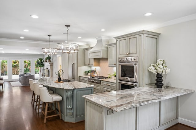 1114 W Cottage St, Houston, TX 77009 - kitchen featuring stainless steel appliances, custom range hood, light stone countertops, recessed lighting, and a kitchen bar