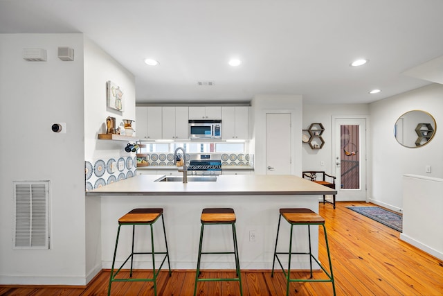 1821 Tuam St, Houston, TX 77004 - kitchen with appliances with stainless steel finishes, a peninsula, a breakfast bar, white cabinetry, and light countertops