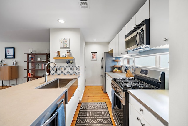 1821 Tuam St, Houston, TX 77004 - kitchen featuring appliances with stainless steel finishes, light countertops, white cabinetry, light wood-style flooring, and recessed lighting
