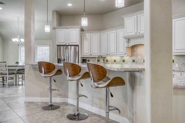 29114 Davenport Dr, Katy, TX 77494 - kitchen with stainless steel fridge with ice dispenser, backsplash, a kitchen breakfast bar, light stone countertops, and recessed lighting