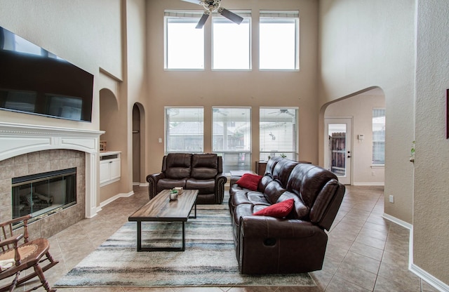 20303 Misty River Way, Cypress, TX 77433 - living area featuring a ceiling fan, arched walkways, tile patterned floors, a high ceiling, and a tile fireplace