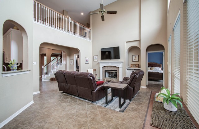 20303 Misty River Way, Cypress, TX 77433 - living room with a ceiling fan, a high ceiling, light tile patterned floors, arched walkways, and a tiled fireplace