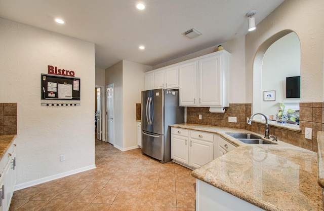 20303 Misty River Way, Cypress, TX 77433 - kitchen with freestanding refrigerator, light stone counters, white cabinetry, arched walkways, and recessed lighting