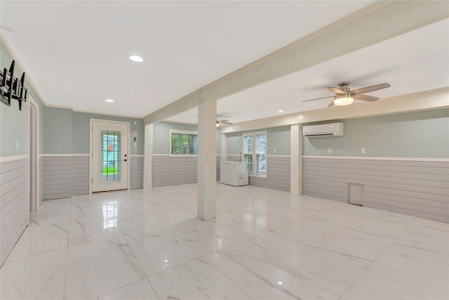 902 Grove Rd, Clear Lake Shores, TX 77565 - empty room featuring a wainscoted wall, a wall mounted air conditioner, a ceiling fan, wooden walls, and marble finish floors