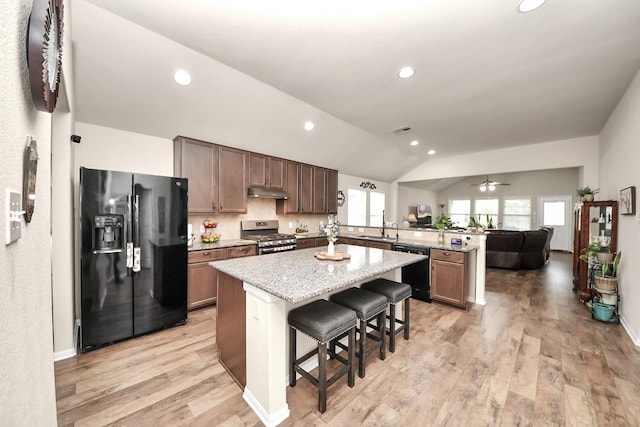 32726 Timber Point Dr, Brookshire, TX 77423 - kitchen featuring black appliances, a peninsula, vaulted ceiling, a kitchen island, and light wood-type flooring