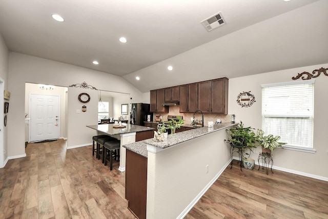 32726 Timber Point Dr, Brookshire, TX 77423 - kitchen with black refrigerator with ice dispenser, range with gas stovetop, lofted ceiling, under cabinet range hood, and wood finished floors