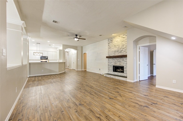 18511 Yellowstone Trl, Humble, TX 77346 - unfurnished living room with a ceiling fan, light wood-style floors, arched walkways, a stone fireplace, and recessed lighting