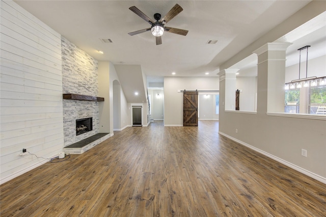 18511 Yellowstone Trl, Humble, TX 77346 - unfurnished living room with a barn door, a ceiling fan, wood finished floors, a stone fireplace, and recessed lighting