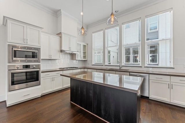 9635 Riddlewood Ln, Houston, TX 77025 - kitchen featuring appliances with stainless steel finishes, ornamental molding, dark wood-style floors, backsplash, and hanging light fixtures