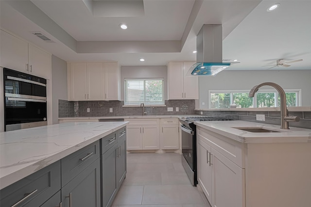 4414 Lemac Dr, Houston, TX 77096 - kitchen with stainless steel range with gas cooktop, island exhaust hood, backsplash, gray cabinetry, and recessed lighting