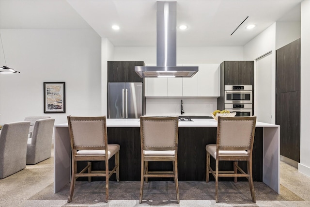 2014 Colquitt, Houston, TX 77098 - kitchen featuring stainless steel appliances, island range hood, modern cabinets, light countertops, and a breakfast bar area