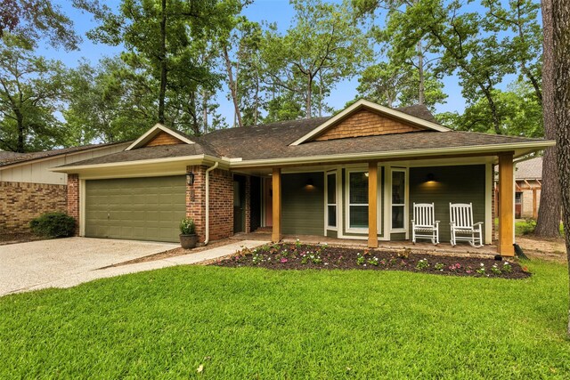 79 Fallshire Dr, The Woodlands, TX 77381 - view of front of property featuring covered porch, an attached garage, a front lawn, brick siding, and concrete driveway