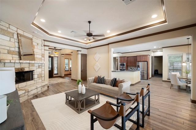 11399 Fm-3126, Livingston, TX 77351 - living area featuring a tray ceiling, ceiling fan, crown molding, a fireplace, and light wood-style floors