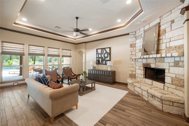 11399 Fm-3126, Livingston, TX 77351 - living room with a raised ceiling, ornamental molding, a ceiling fan, wood finished floors, and a stone fireplace