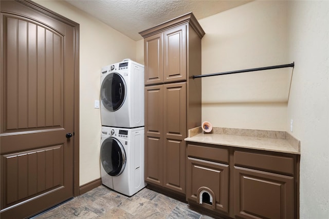 11399 Fm-3126, Livingston, TX 77351 - washroom featuring stacked washing machine and dryer, cabinet space, a textured ceiling, and light stone finish flooring