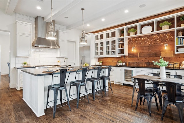 523 E 23rd St, Houston, TX 77008 - kitchen with beverage cooler, dark countertops, wall chimney range hood, beam ceiling, and dark wood-style floors