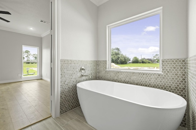 15408 Sandtrap Dr, Waller, TX 77484 - bathroom with tile walls, crown molding, a soaking tub, wood finished floors, and a wainscoted wall
