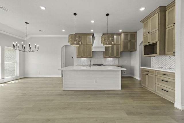 15408 Sandtrap Dr, Waller, TX 77484 - kitchen featuring custom exhaust hood, a chandelier, tasteful backsplash, arched walkways, and a center island with sink