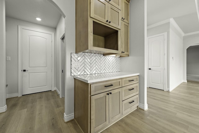 15408 Sandtrap Dr, Waller, TX 77484 - kitchen with arched walkways, crown molding, light countertops, decorative backsplash, and light wood-type flooring