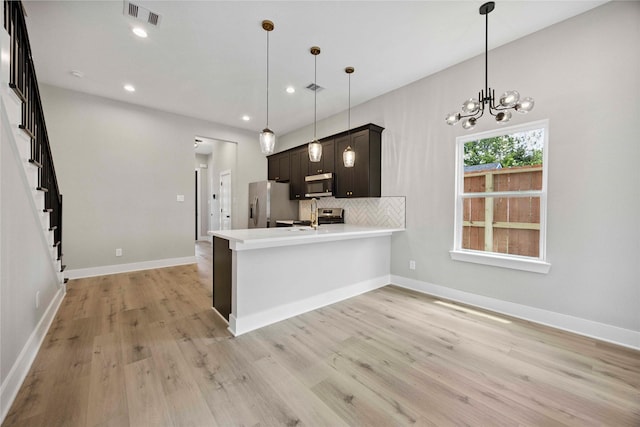 217 Pheasant St, Houston, TX 77018 - kitchen with appliances with stainless steel finishes, a peninsula, light wood-type flooring, light countertops, and backsplash