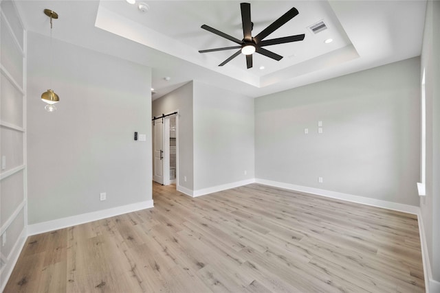 217 Pheasant St, Houston, TX 77018 - empty room with a tray ceiling, a ceiling fan, a barn door, light wood finished floors, and recessed lighting