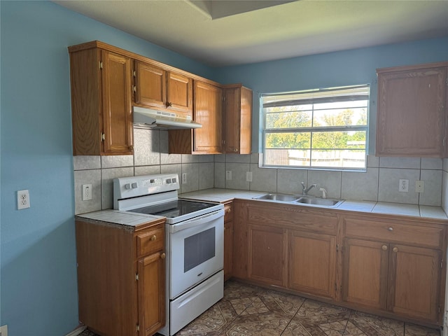 5518 Rio Ramos St, Rosharon, TX 77583 - kitchen featuring white electric range oven, under cabinet range hood, tile countertops, tasteful backsplash, and brown cabinets