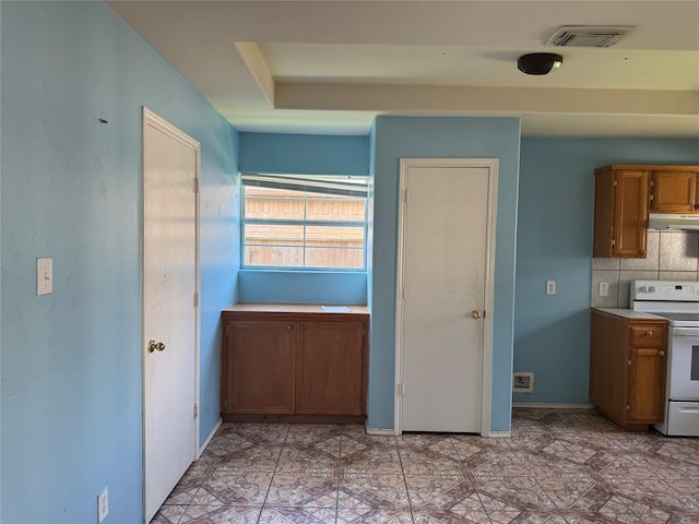 5518 Rio Ramos St, Rosharon, TX 77583 - kitchen with white range with electric cooktop, under cabinet range hood, brown cabinets, backsplash, and light countertops