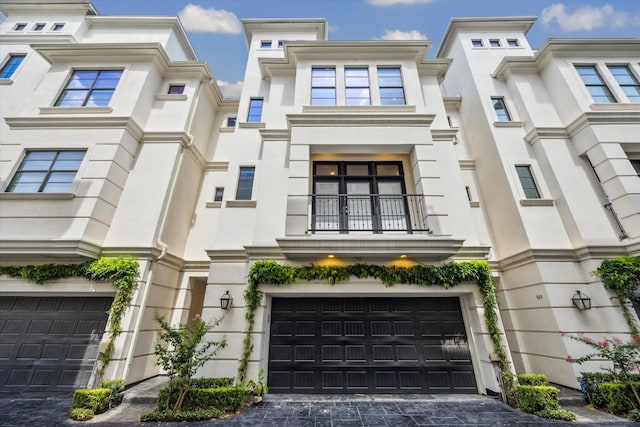 521 W Bell St, Houston, TX 77019 - view of front of home with a balcony, an attached garage, decorative driveway, and stucco siding