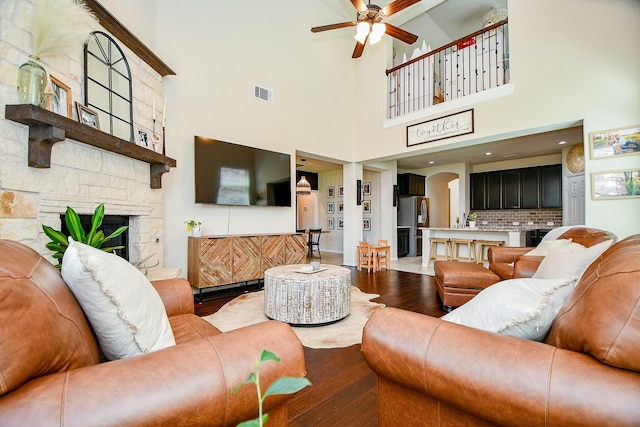 29011 Oldfield Ct, Katy, TX 77494 - living area featuring hardwood / wood-style flooring, a ceiling fan, arched walkways, a fireplace, and a high ceiling
