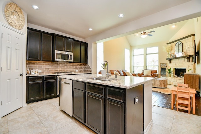 29011 Oldfield Ct, Katy, TX 77494 - kitchen with stainless steel appliances, a ceiling fan, light tile patterned floors, backsplash, and an island with sink