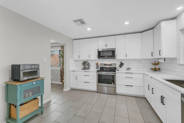 19702 Franz Rd, Houston, TX 77084 - kitchen featuring appliances with stainless steel finishes, backsplash, light countertops, white cabinetry, and recessed lighting