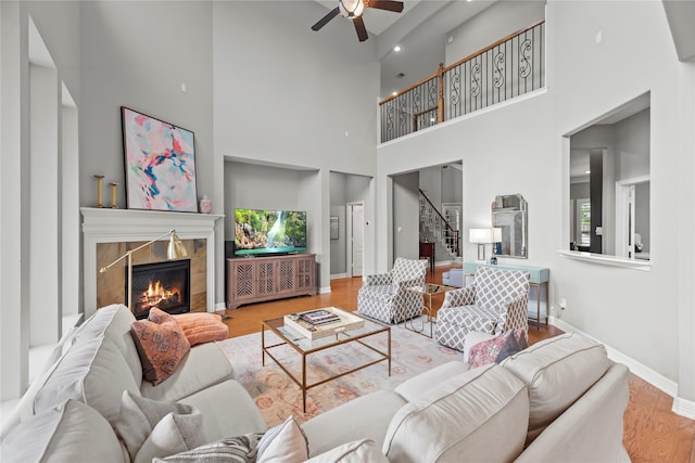 27410 Villa Mountain Ct, Fulshear, TX 77441 - living room with a tiled fireplace, stairway, a ceiling fan, wood finished floors, and a high ceiling