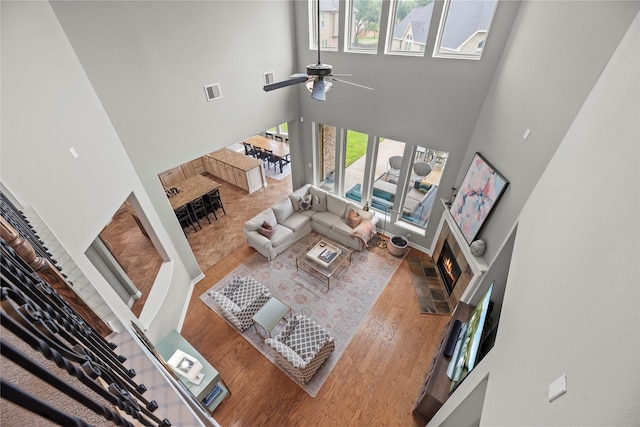 27410 Villa Mountain Ct, Fulshear, TX 77441 - living area featuring a high ceiling, a lit fireplace, ceiling fan, wood finished floors, and stairway