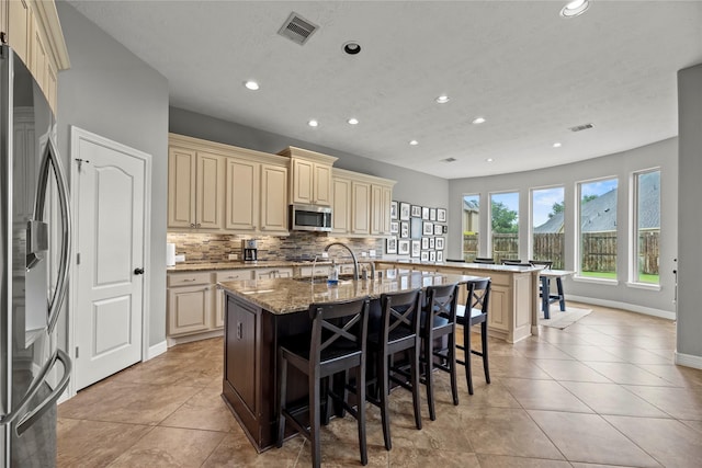 27410 Villa Mountain Ct, Fulshear, TX 77441 - kitchen featuring cream cabinets, appliances with stainless steel finishes, a kitchen bar, recessed lighting, and a center island with sink
