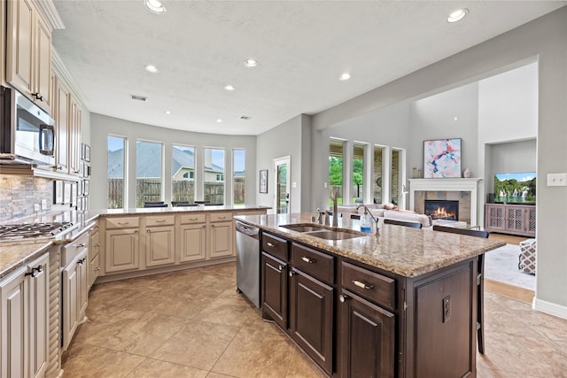 27410 Villa Mountain Ct, Fulshear, TX 77441 - kitchen featuring stainless steel appliances, cream cabinetry, recessed lighting, a fireplace, and light stone counters