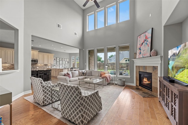 27410 Villa Mountain Ct, Fulshear, TX 77441 - living area featuring light wood finished floors, a fireplace, a ceiling fan, and a towering ceiling