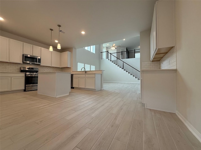 8116 Tourmaline Way, Texas City, TX 77591 - kitchen featuring appliances with stainless steel finishes, decorative backsplash, light wood-style floors, ceiling fan, and recessed lighting