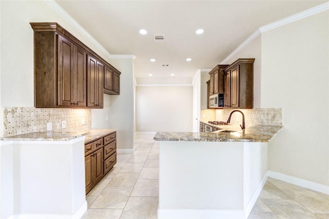 4927 Caponi Falls Ln, Katy, TX 77494 - kitchen featuring backsplash, stainless steel microwave, light stone counters, ornamental molding, and recessed lighting
