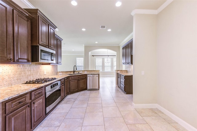 4927 Caponi Falls Ln, Katy, TX 77494 - kitchen featuring appliances with stainless steel finishes, arched walkways, ornamental molding, decorative backsplash, and a peninsula