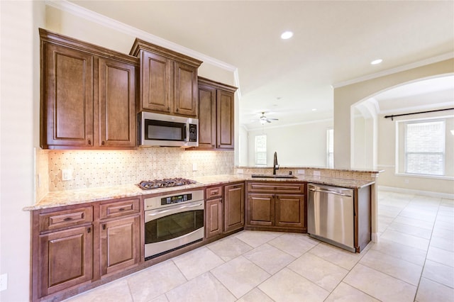 4927 Caponi Falls Ln, Katy, TX 77494 - kitchen with appliances with stainless steel finishes, crown molding, arched walkways, decorative backsplash, and a peninsula