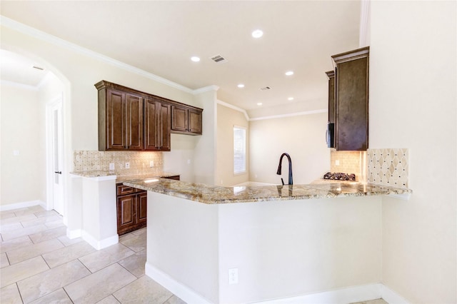 4927 Caponi Falls Ln, Katy, TX 77494 - kitchen featuring decorative backsplash, arched walkways, light stone countertops, a peninsula, and ornamental molding